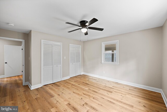 unfurnished bedroom with multiple closets, ceiling fan, and light wood-type flooring