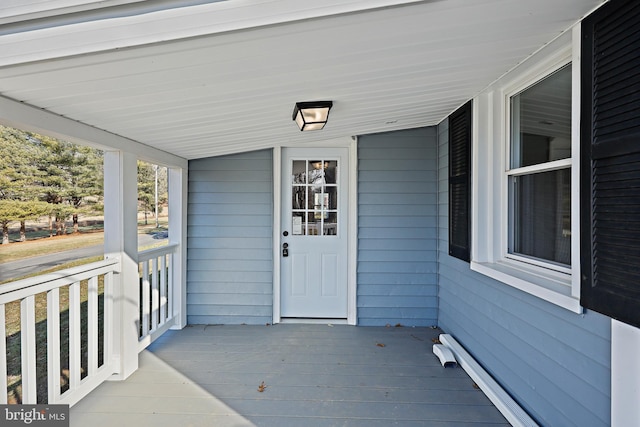 view of exterior entry with a baseboard heating unit and covered porch