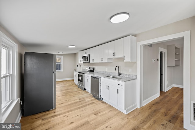 kitchen featuring sink, light hardwood / wood-style flooring, appliances with stainless steel finishes, light stone countertops, and white cabinets