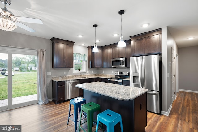 kitchen featuring appliances with stainless steel finishes, decorative light fixtures, a breakfast bar area, a center island, and dark brown cabinets