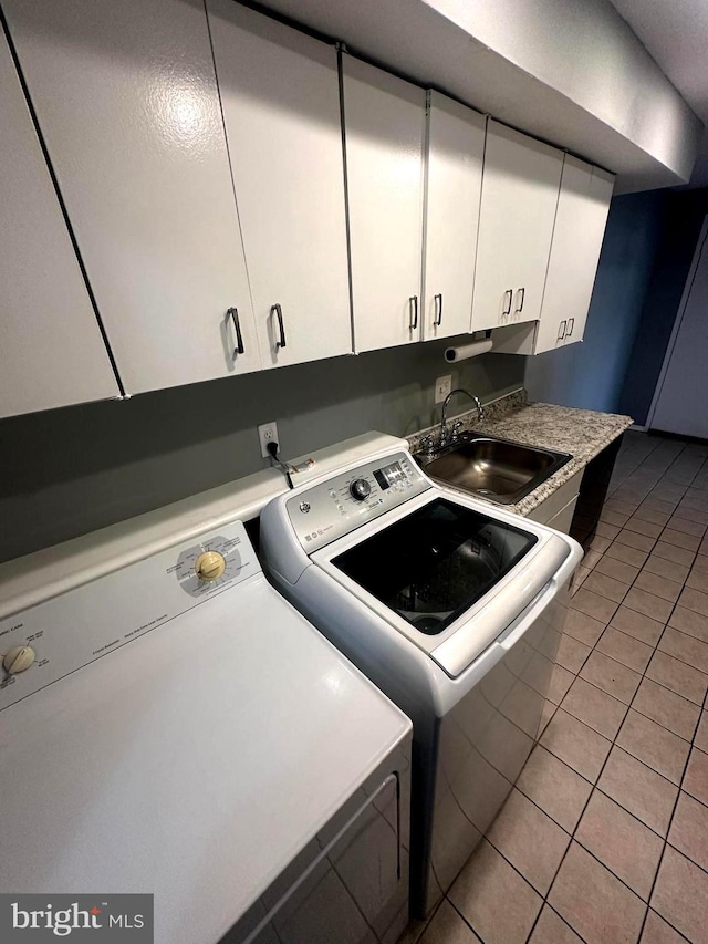 laundry room featuring sink, light tile patterned floors, washer and clothes dryer, and cabinets