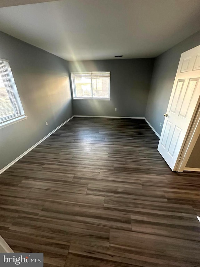 unfurnished room with dark wood-type flooring