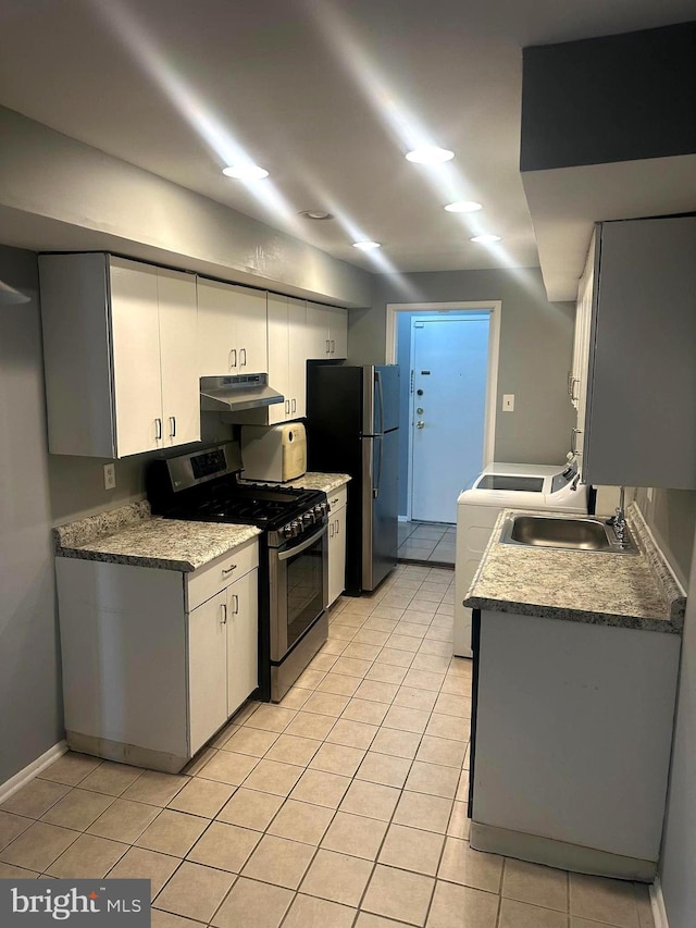 kitchen featuring sink, light tile patterned floors, appliances with stainless steel finishes, white cabinetry, and washer / dryer