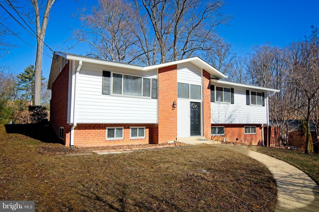 raised ranch with brick siding and a front yard