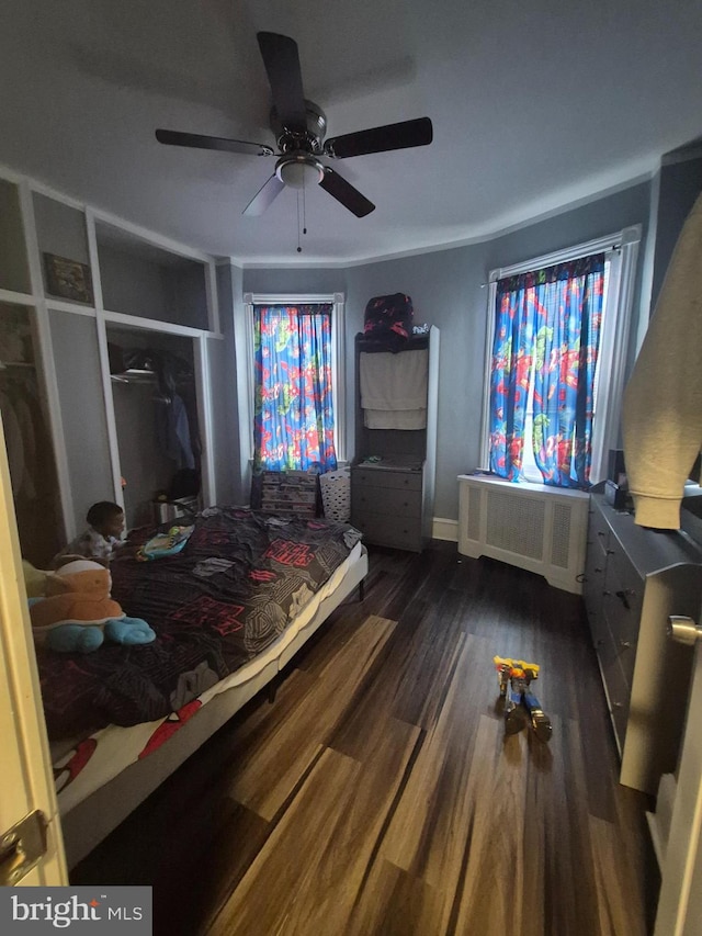 bedroom with dark wood-type flooring, radiator heating unit, and ceiling fan