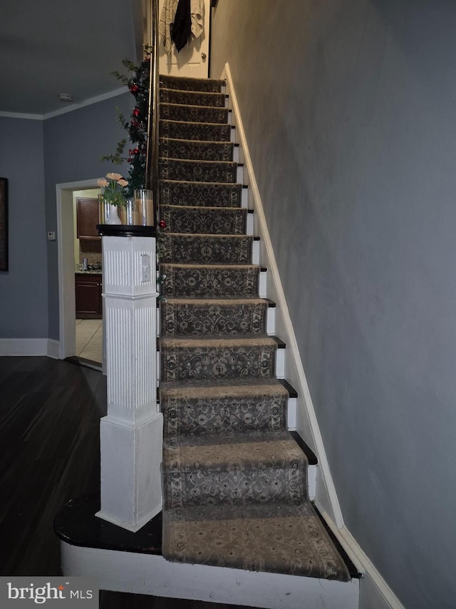 stairs featuring crown molding and hardwood / wood-style floors