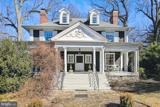 neoclassical / greek revival house with covered porch, a shingled roof, and a chimney