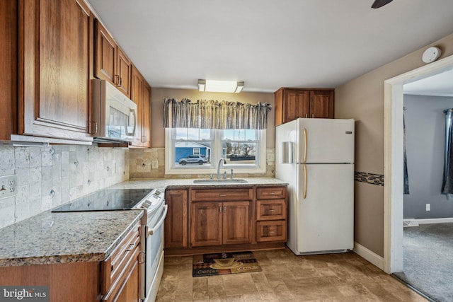 kitchen featuring tasteful backsplash, sink, white appliances, and light stone counters