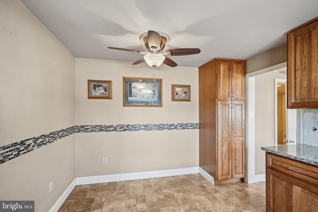 kitchen featuring light stone counters and ceiling fan