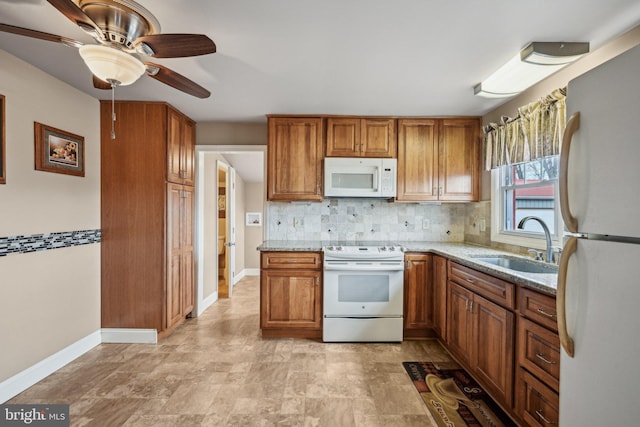 kitchen with sink, light stone counters, ceiling fan, white appliances, and backsplash