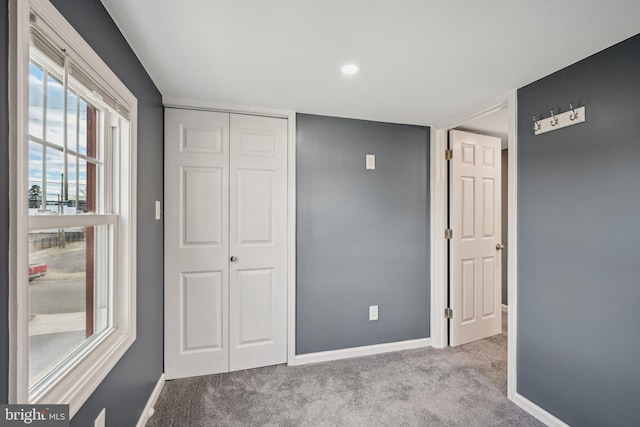 unfurnished bedroom with light colored carpet and a closet