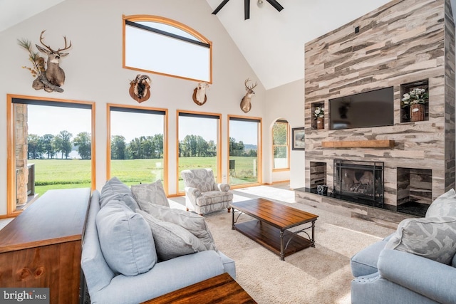 living room with a tiled fireplace, ceiling fan, light carpet, and high vaulted ceiling