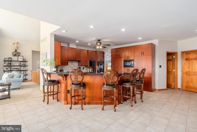 kitchen featuring a kitchen breakfast bar, black appliances, light tile patterned flooring, decorative backsplash, and kitchen peninsula