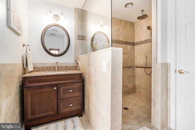 bathroom featuring vanity, a tile shower, and tile walls