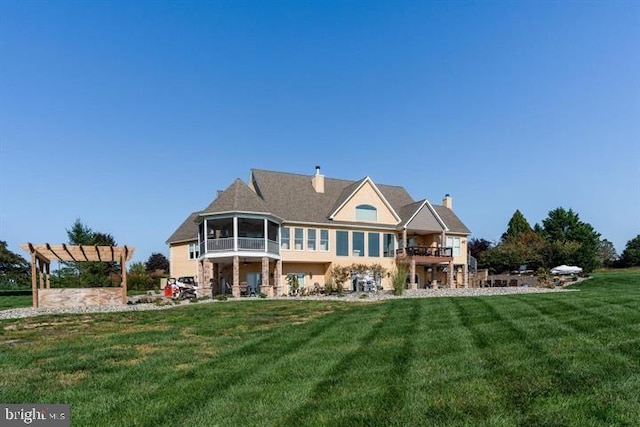 rear view of house with a sunroom, a lawn, and a pergola