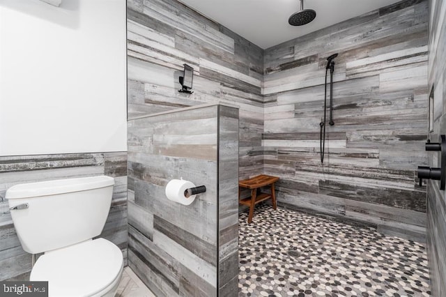 bathroom with toilet, tile walls, and a tile shower