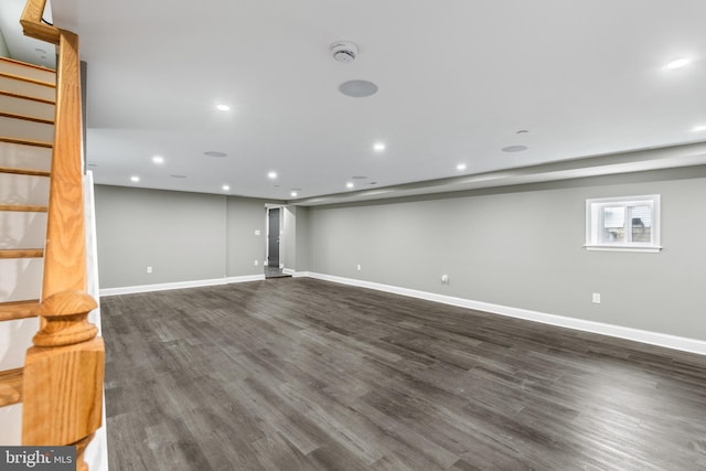 basement featuring baseboards, dark wood finished floors, and stairs