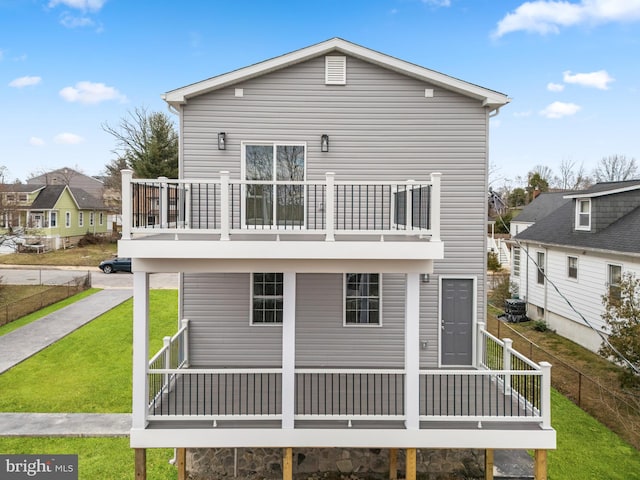 back of property featuring a lawn, a balcony, and fence