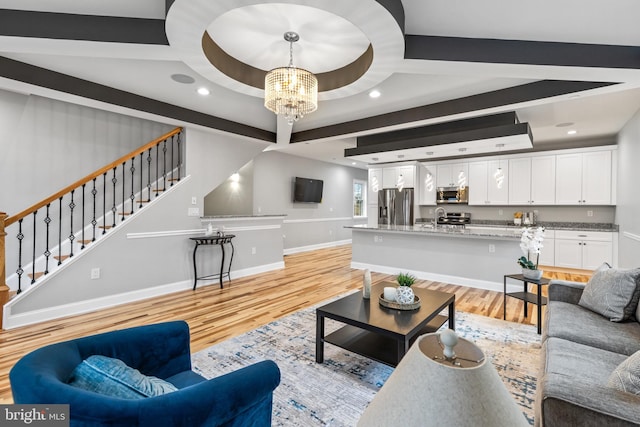 living area featuring light wood finished floors, baseboards, stairway, recessed lighting, and an inviting chandelier