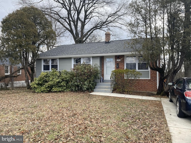 view of front of house with a shingled roof, brick siding, and a chimney