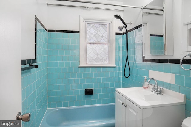 full bath featuring tile walls, shower / bathing tub combination, and vanity