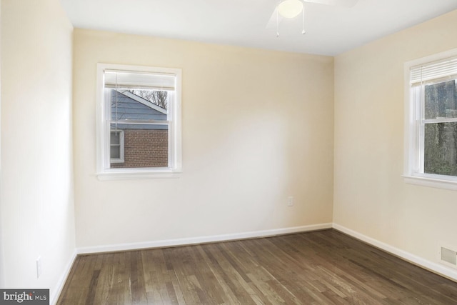 spare room with baseboards and dark wood-style flooring