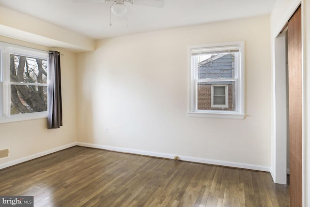 unfurnished room featuring dark wood-style floors, visible vents, ceiling fan, and baseboards