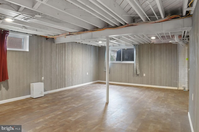 basement featuring baseboards, wood finished floors, and wooden walls