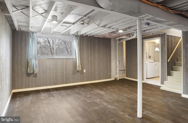 basement with wooden walls, dark wood finished floors, stairway, and washing machine and clothes dryer