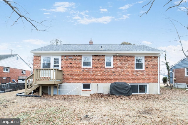 back of house featuring brick siding, a chimney, a shingled roof, and fence