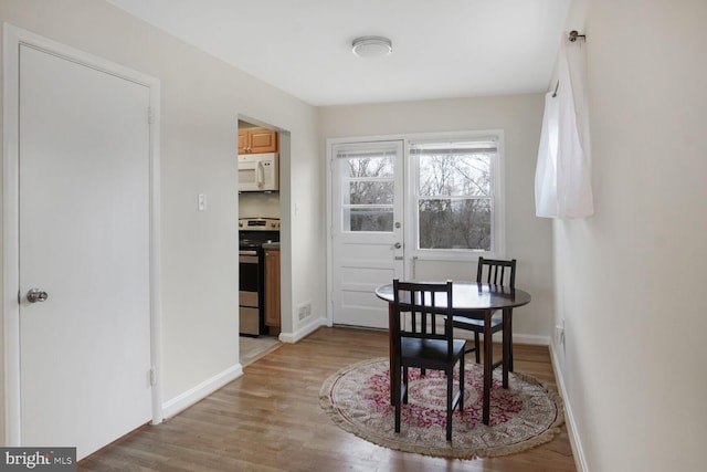 dining area featuring light wood-type flooring, visible vents, and baseboards