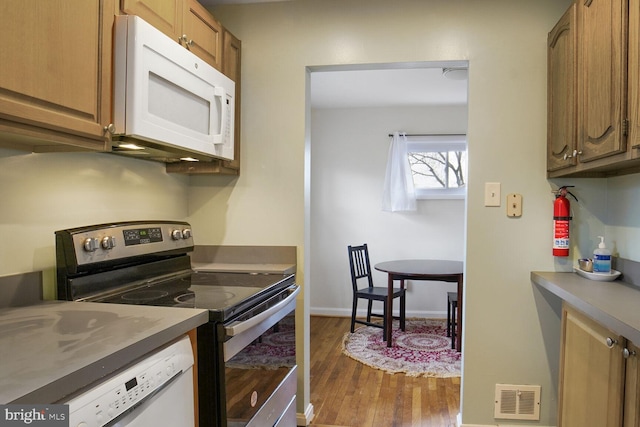 kitchen featuring white appliances, dark wood-style flooring, visible vents, baseboards, and brown cabinets