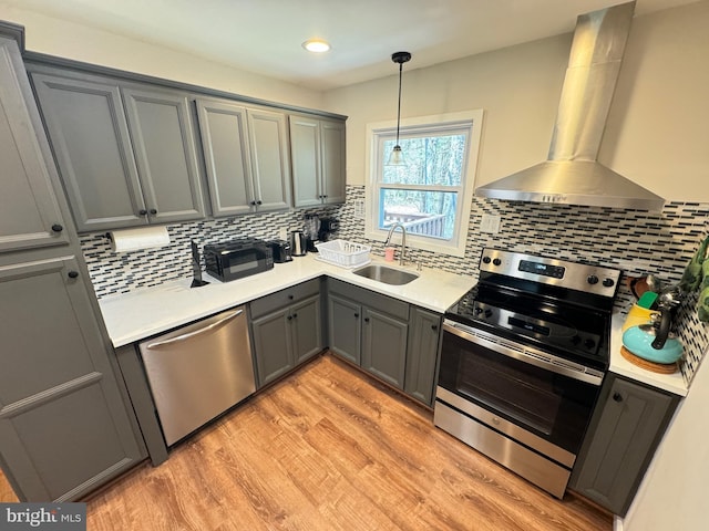 kitchen with stainless steel appliances, sink, wall chimney range hood, and gray cabinetry