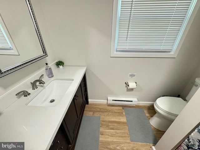 bathroom with vanity, wood-type flooring, a baseboard heating unit, and toilet