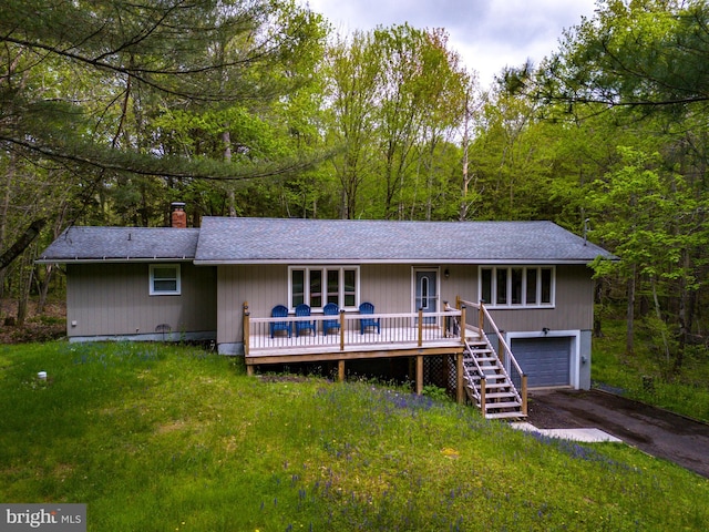 single story home featuring a wooden deck, a garage, and a front lawn