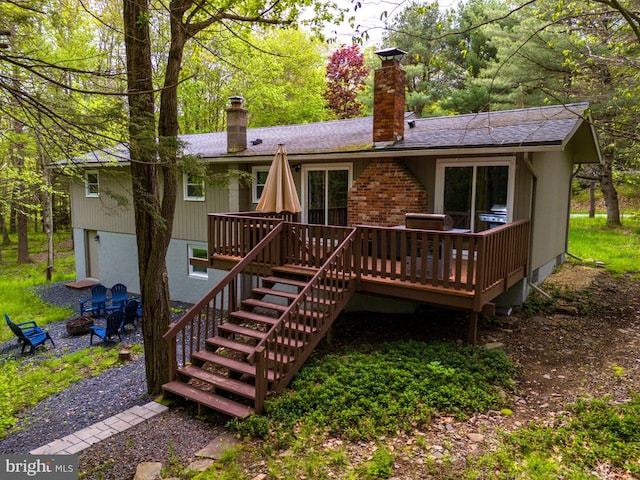 back of property featuring a fire pit and a deck