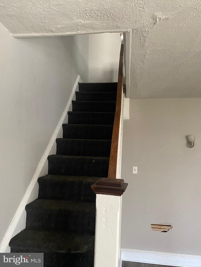 staircase featuring a textured ceiling