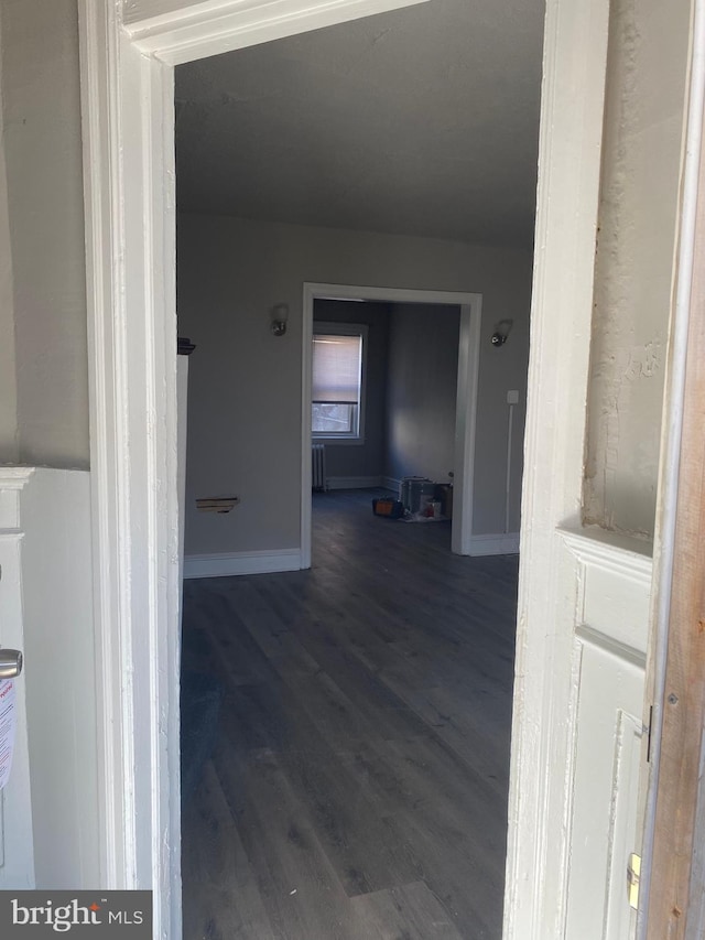 hallway with dark wood-type flooring and radiator