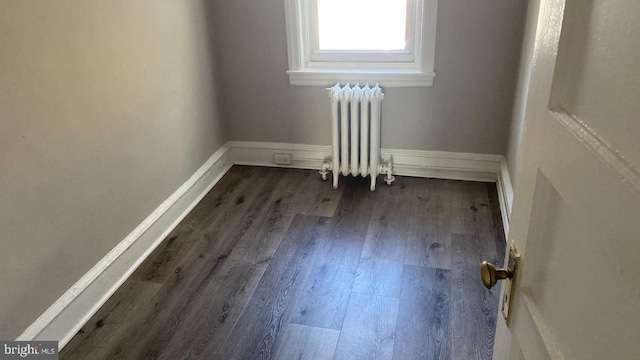 empty room featuring dark hardwood / wood-style flooring and radiator