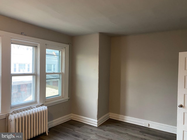 empty room featuring dark wood-type flooring and radiator heating unit