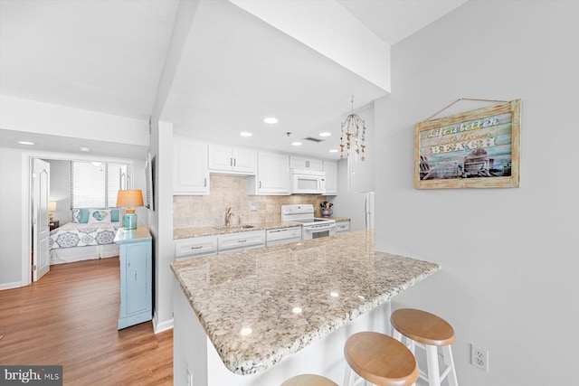 kitchen with pendant lighting, white cabinetry, sink, white appliances, and light hardwood / wood-style flooring