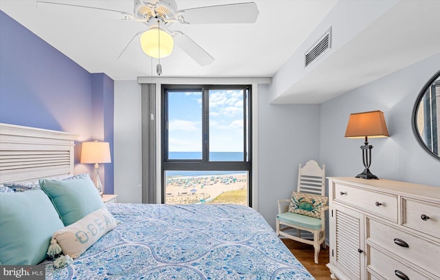 bedroom with dark wood-type flooring, ceiling fan, and a water view