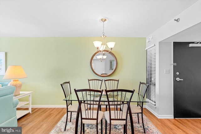 dining area with light hardwood / wood-style floors and a notable chandelier