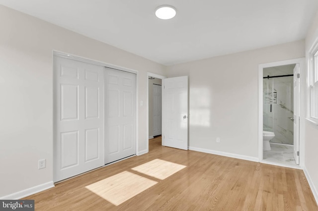 unfurnished bedroom featuring a closet, connected bathroom, and light hardwood / wood-style flooring