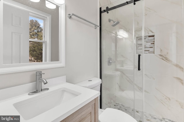 bathroom with a shower with door, vanity, and toilet