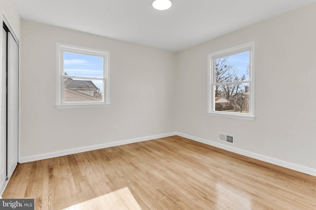 unfurnished bedroom with multiple windows, hardwood / wood-style flooring, and a closet