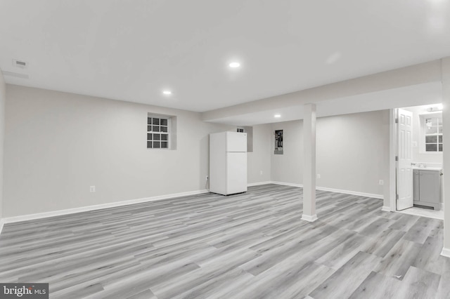 basement featuring white refrigerator and light hardwood / wood-style flooring