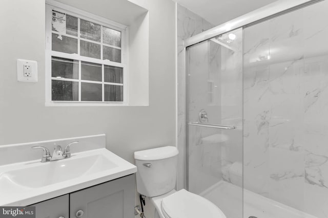 bathroom featuring vanity, a shower with door, and toilet