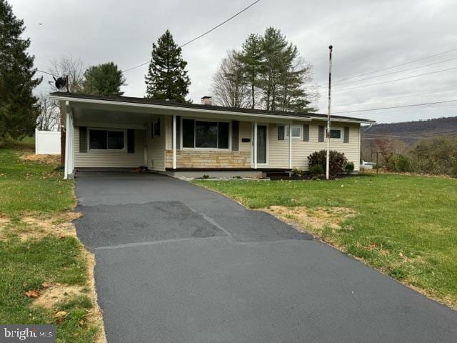 ranch-style home with driveway, stone siding, a front lawn, and a carport