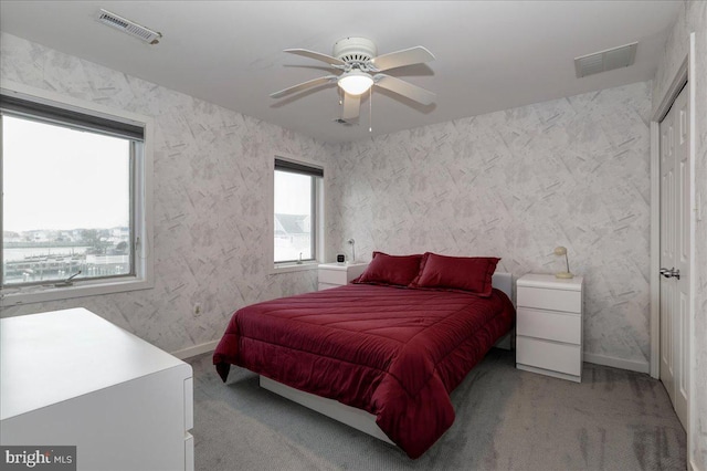 carpeted bedroom featuring multiple windows and ceiling fan